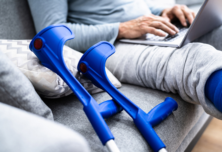 Person with crutches using computer